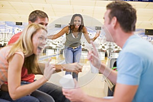 Four young adults laughing at a bowling alley