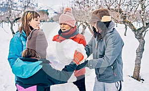 Four Young Caucasian Girls Wearing Gloves Enjoying Making a Snowman