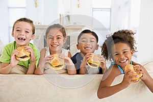 Four young children eating cheeseburgers