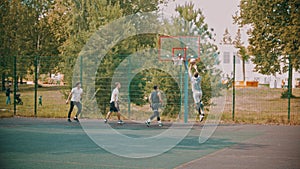 Four young friends playing basketball on the sports ground