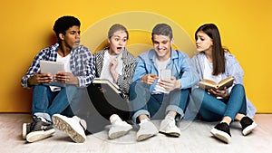 Four Young Friends Sharing Excitement Over Smartphone Content Against Yellow