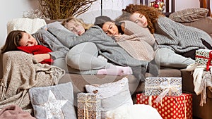 Four young girls fell asleep on the couch after wrapping Christmas presents