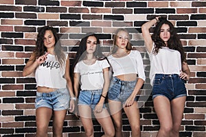 Four young girls in white t-shirts and jeans shorts standing nea