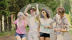 Four young happy people jumping, putting hands in air, dancing at music festival