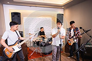 four young men as a band sing songs and play musical instruments during sound check