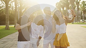 Four young multiracial friends making selfie under warm sunlight outdoors on summer day