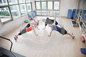 Four young people stretching and looking at the camera in an aerobics class