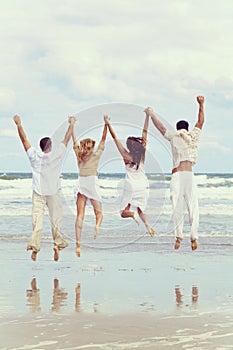 Four Young People Two Couples Jumping in Celebration On Beach