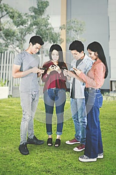 Four young people use mobile phone in the park