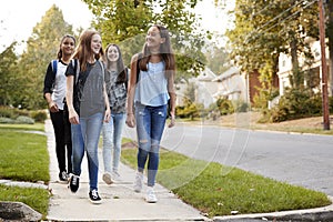 Four young teen girls walking to school together, front view