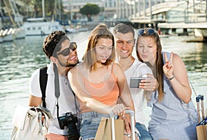 Four young travellers making selfie with smartphone