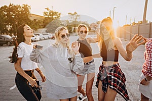 Four young women dance in a car park