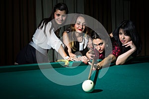 Four young women have fun with playing billiard