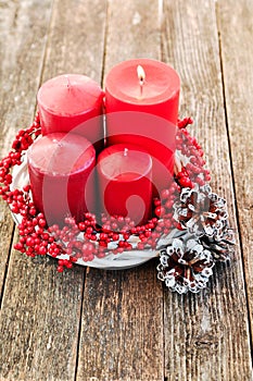 Four candles in a white wreath with red berries on a wooden rustic background with lights. advent calendar for Christmas