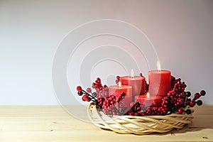 Fourth advent with four red candles, all are lighted, decorated in a natural willow wicker wreath with artificial berries, holiday