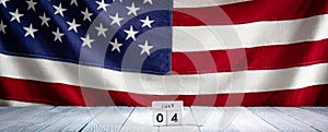 Fourth Of July date on wooden block calendar on background of US flag. USA Independence Day background