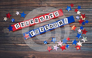 Fourth of July Sign with Words that say Celebrate Freedom.  It`s in red, white and blue with shiny stars with light reflections,