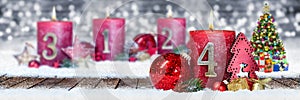 fourth sunday of advent red candle with golden metal number one on wooden planks in snow front of silver bokeh background