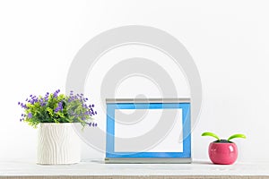 Fowers and blue frame on a white with wall shelf. photo