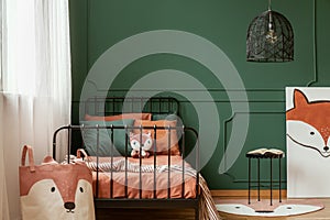 Fox kid bedroom interior with molding on green wall and orange sheets on the bed. Real photo