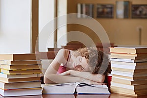 Foxy haired female student fall asleep while reading book for finding information, preparing for exams, woman laing at table,