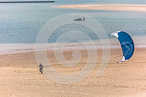 View of a male professional Kiteboarder walking on the sand beach, at the Obidos lagoon