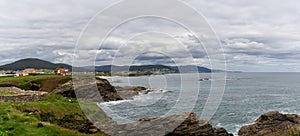 Coastline in Galicia near Foz with green meadows and homes on the seashore photo