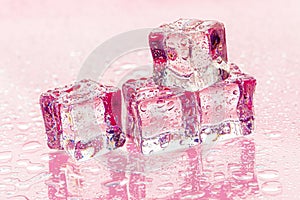 Fozen ice cubes on wet pink background photo