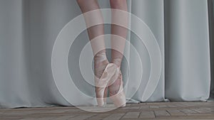 Fragile ballerina dancing ballet on the tiptoes, feet in pointe tied with ribbons closeup on white background. Slow