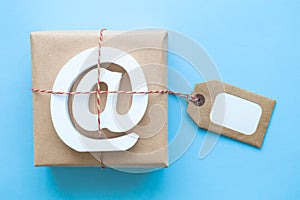 Fragile parcel wrapped in brown paper with e-mail wooden sign and label against blue background