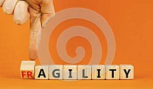 Fragility or agility symbol. Concept words Fragility and Agility on wooden cubes. Beautiful orange table orange background.