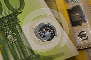 A fragment of a 100 euro banknote with a hologram. Eurozone currency fragment.