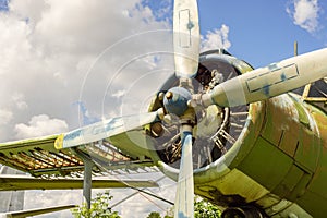 A fragment of airplane wing with four-bladed aircraft propeller against blue sky