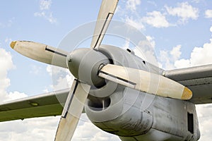 A fragment of airplane wing with four-bladed aircraft propeller against blue sky