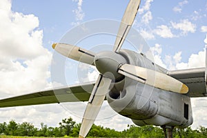 A fragment of airplane wing with four-bladed aircraft propeller against blue sky