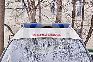 Fragment of an ambulance car on a background of leafless trees