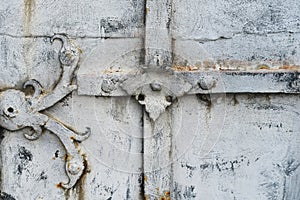 Fragment of ancient peeling and decayed monastery gates with rusty skillfully forged hinges and decorative overlays.