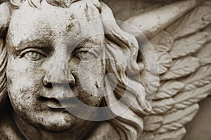 Fragment of ancient statue of angel with wings and green eyes