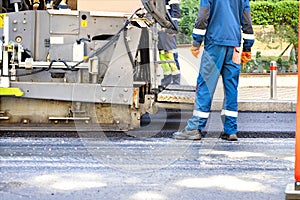 Fragment of applying fresh asphalt in the work of an asphalt paver on the road on a summer day