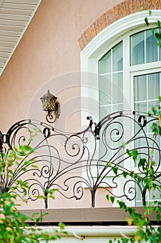 A fragment of a beautiful country house with a window and an openwork metal grill. Vertical photo