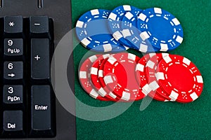 Fragment of black keyboard with gamble chips.