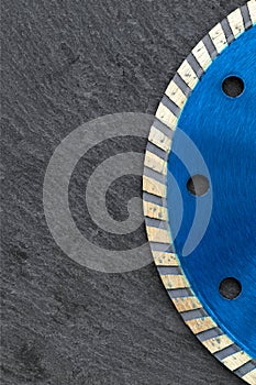 Fragment of a blue diamond cutting wheel on a gray granite background. Copy space. Vertical image