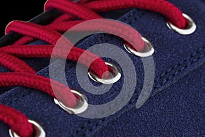 A fragment of a blue sneaker with red laces