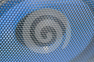 Fragment of the blue speaker with a black metal perforated grille. Audio speaker grill texture closeup view. Selective focus