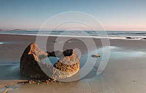 Fragment of a boulder on the ocean shore at sunrise