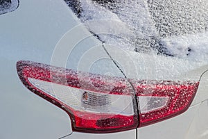 Fragment of car with tail lamps, covered with fluffy snow