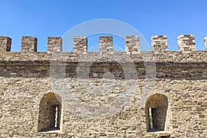 Fragment of a castle wall of a fortress fortification made of natural stone.