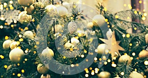 Fragment close up of a decorated christmas tree with golden balls and garland. Winter holiday background