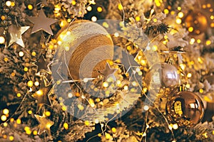 Fragment close up of a decorated christmas tree with golden balls and garland. Winter holiday background