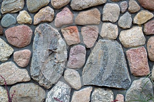 Fragment of a colored stonewall. Natural big textured stone. background